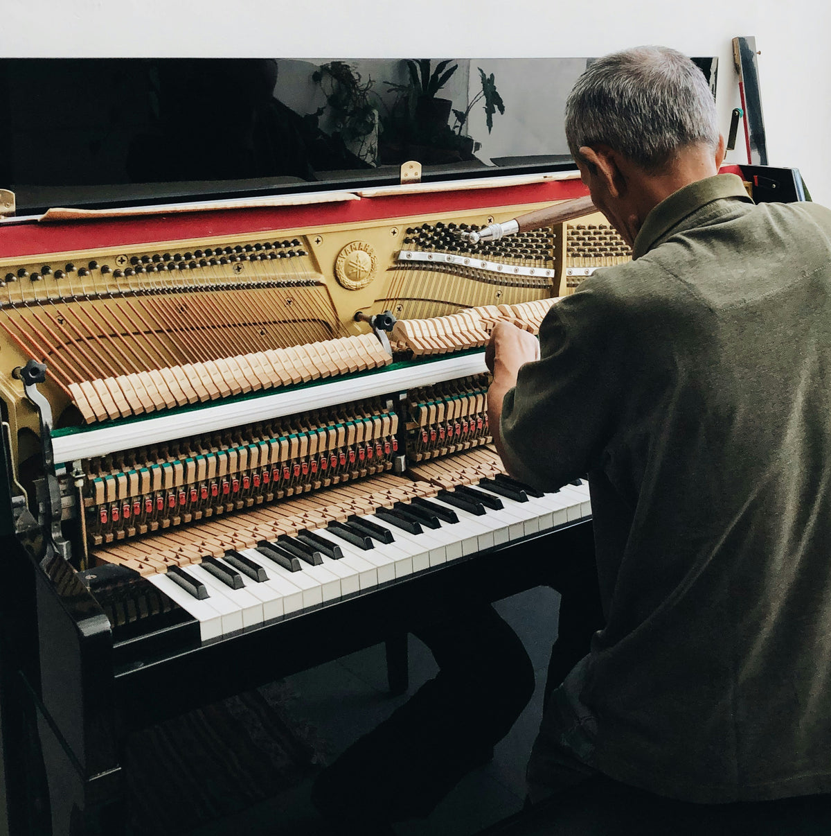 Hands playing an acoustic piano keyboard during technical piano service evaluation